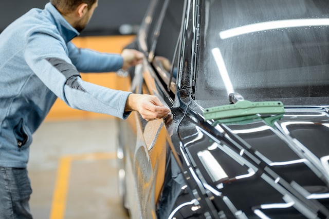 car service worker sticking anti-gravel film on a car body