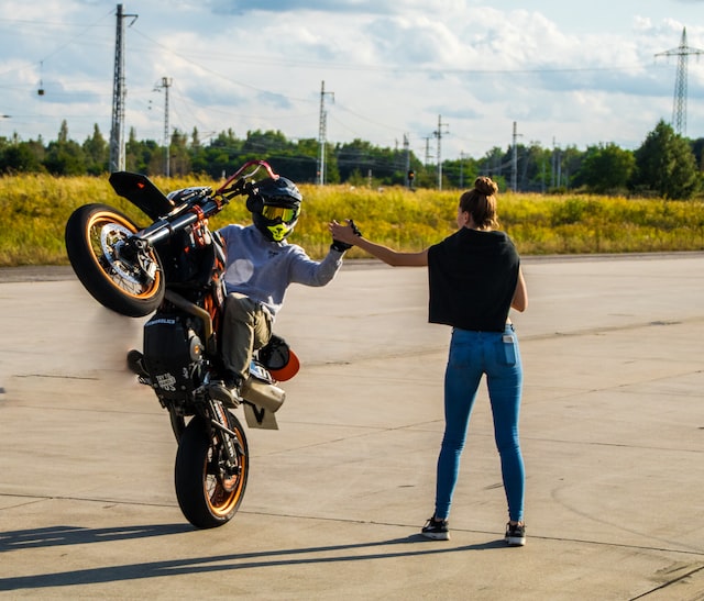 man in black t-shirt and blue denim jeans riding motorcycle on road
