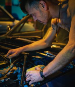 man in black tank top repairing car