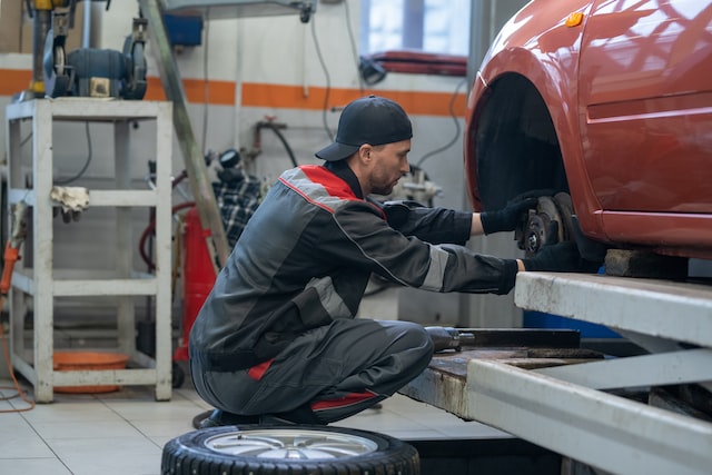 repairman in workwear changing wheel