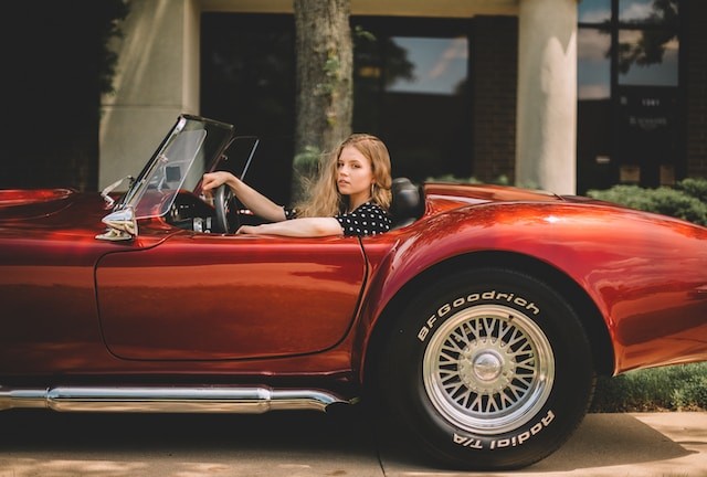 Woman riding classic red convertible car